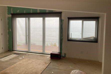 Stylish automatic window treatments installation process in a bright Laguna Beach living area.